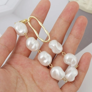 Detail shot of irregular baroque pearl bracelet with gold metal clasp on hand
