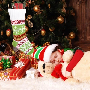 Knitted Christmas stocking with snowflake patterns hung in a cozy holiday bedroom scene