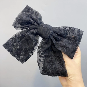 Close-up of black double-layered lace bow hair clip with detailed floral embroidery