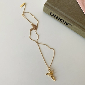 Detail of a minimalist gold 925 sterling silver angel pendant necklace on a white desk