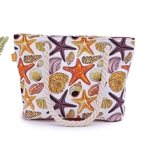 Ocean themed beach tote bag with starfish prints and thick rope handles on white background