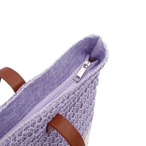Purple woven beach shoulder bag with brown handles and a silver zipper closure