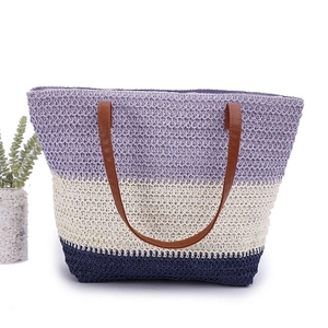 Detail of a woven tote bag featuring purple, beige, and navy stripes with brown leather handles