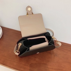 Internal structure of black pebbled leather crossbody bag with beige lining and gold zipper
