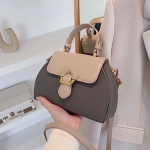 Close-up of litchi texture leather and golden metal buckle on a retro contrast handbag