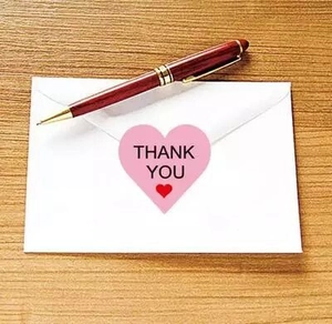 Pink heart-shaped Thank You stickers on a white envelope with a stylish red pen