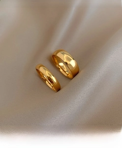 Detailed macro view of gold plated minimalist stacking rings on elegant champagne silk