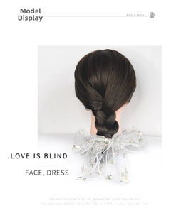 Detail of white mesh hair bow with delicate floral embroidery on a braided hairstyle