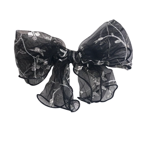 Elegant black silk mesh bow hair clip with silver floral embroidery on white background