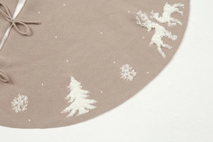 Detailed close-up of taupe knitted Christmas tree skirt with white reindeer embroidery