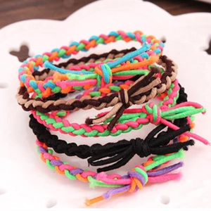 Close-up of colorful braided hair ties with knotted tassels on a white decorative plate