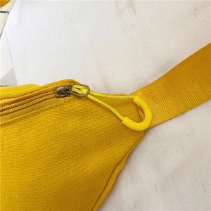 Détail du sac en toile jaune avec fermeture éclair fluide et attache de sangle robuste