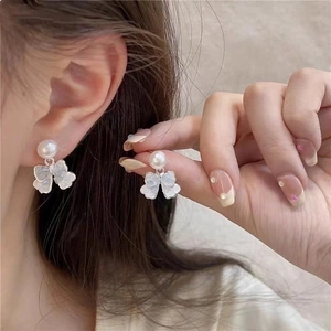 Detailed close-up of heart-shaped pearl bow earrings with iridescent shell texture finish