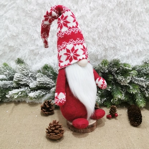 Detail of red Christmas gnome with white snowflake pattern on rustic wooden base