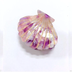 Close-up of shell-shaped acetate hair claw clip with purple marble texture and gold lines