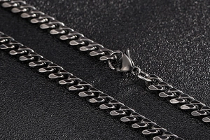 Macro detail of black stainless steel Cuban link necklace featuring a lobster clasp