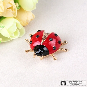 Macro detail of red ladybug brooch with black rhinestones and gold-plated finish