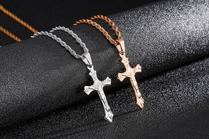 Detail of silver and rose gold stainless steel cross pendants with embossed crucifix
