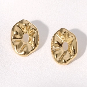 Macro detail of gold irregular wavy earrings with a polished metallic texture finish