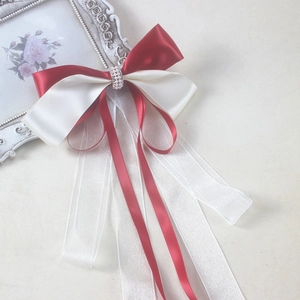 Detailed view of traditional Chinese red and white ribbon hair bow with pearls and long streamers
