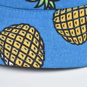 Close-up of royal blue canvas fabric with yellow pineapple print on a sun bucket hat