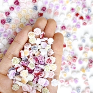 Macro shot of colorful 3D resin rose flower nail art charms on fingertips and palm