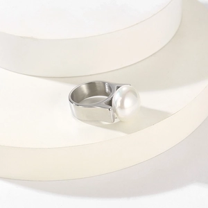 Makroaufnahme: minimalistischer Edelstahlring mit weißer Perle auf geometrischem Sockel