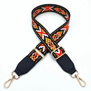 Detail of colorful geometric jacquard bag strap with gold lobster clasps and black leather ends