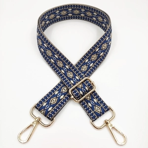 Detail of blue and beige geometric diamond pattern jacquard bag strap with gold metal hardware