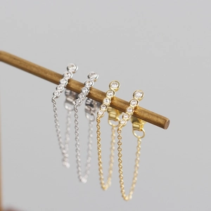 Macro shot of silver and gold tassel chain earrings with shimmering geometric crystals