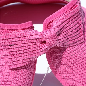 Close-up of rose pink woven visor featuring bow detail and intricate straw texture