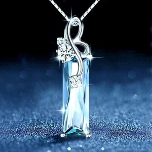 Macro detail of silver rectangle blue crystal pendant with clear stones on box chain