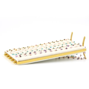 Golden metal jewelry display tray with cream velvet lining showing stone necklaces