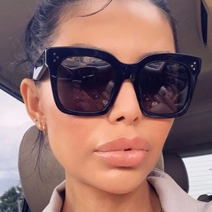 Detailansicht einer schwarzen quadratischen Sonnenbrille mit markanten Metallnieten-Details