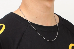 Macro view of silver stainless steel ball and cylinder chain necklace on model