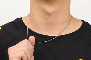 Detailed view of a silver stainless steel oval bead chain necklace on a model's neck