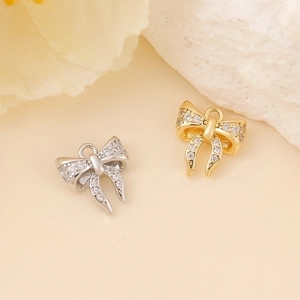 Detail of gold and silver bow pendants with clear stones on peach background