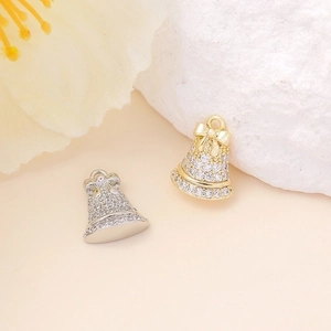 Close-up of gold and silver bell pendants with zircon bows for DIY jewelry making