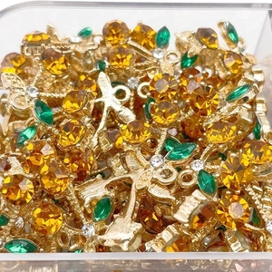 Macro shot of gold cherry pendants with yellow faceted zircons and green leaf gems