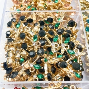 Macro detail of cherry leaf and flower pendants with colored zircon in a sorting box