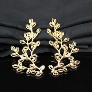 Elegant gold leaf branch earrings with hollow design on professional black background