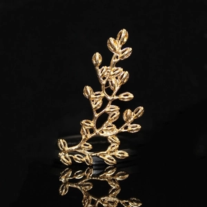 Detail shot of a golden tree branch ring with artistic texture on a black reflective surface