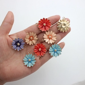 Handheld view of colorful daisy flower alloy charms with gold backing for DIY jewelry making