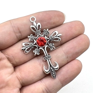 Gothic punk silver cross pendant featuring a central red gemstone held in hand