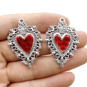 Zinc alloy silver sacred heart pendants with red enamel center held in hand
