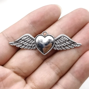 Vintage silver gothic heart wing pendant displayed on hand for scale and detail