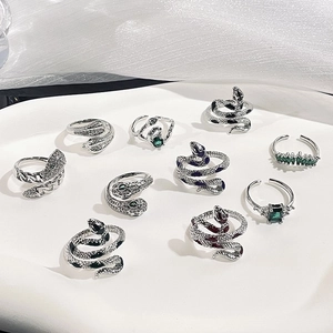 Gothic silver snake rings set with green zircon stones in a minimalist aesthetic style