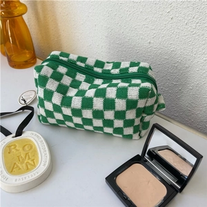 Detailed shot of green and white checkered knit toiletry bag with textured weave and zipper
