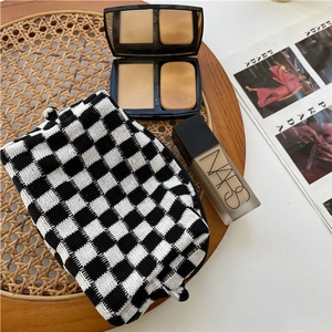 Macro shot of knitted checkerboard makeup bag featuring a durable zipper and soft texture
