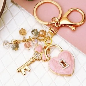 Detail of a gold-plated keychain with pink heart charm, crystal key and colorful beads